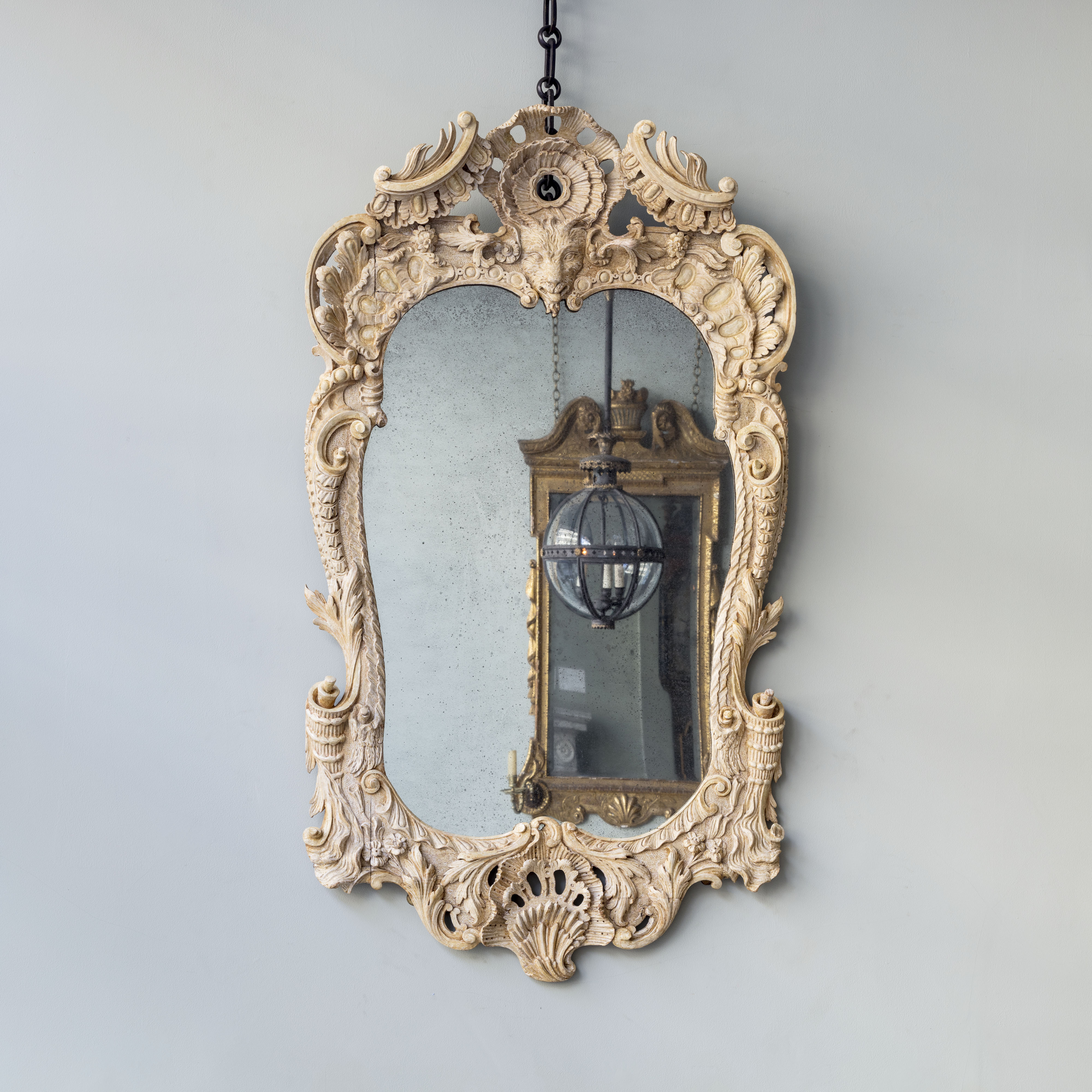 An Exceptional Rococo Carved Giltwood Pier Mirror with Central Goat Mask with profuse scrolling pediment enclosing foliate and shell cartouche and central goat mask, within scolling cornucopia and acanthus border, and pierced shell apron. English c. 1740.